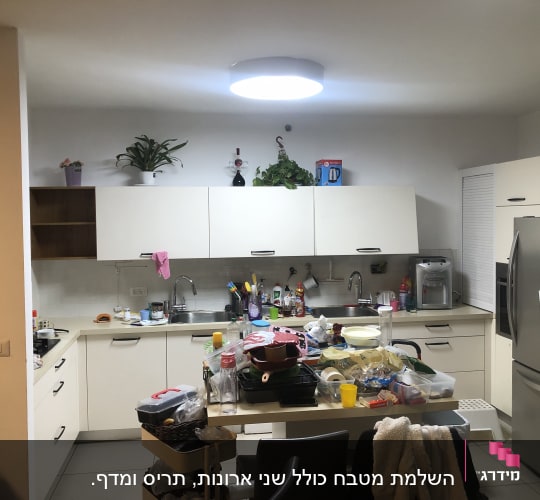 מטבח עם ארונות לבנים, כיור, מקרר וכלים על השיש